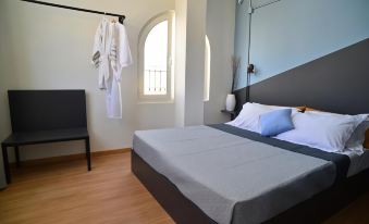 a neatly made bed with a gray blanket and white robe hanging on the wall in a room at Habit