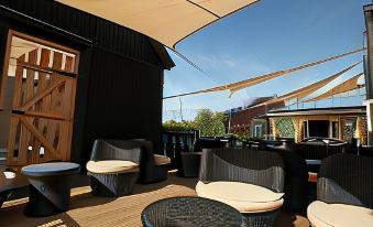 a wooden deck with several chairs and tables , some of which are covered with black fabric at The Cadogan Arms