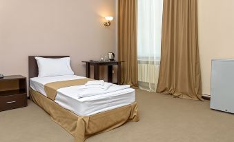a neatly made bed with white sheets and a gold blanket is in a room with beige walls at Richmind Hotel
