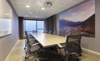 a conference room with a large table and chairs , surrounded by windows and a mountain mural on the wall at Scandic Narvik