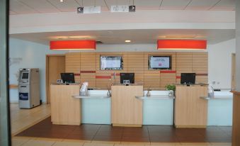 a modern office reception area with wooden walls , three computer monitors , and a green desk at Ibis Lagos Ikeja