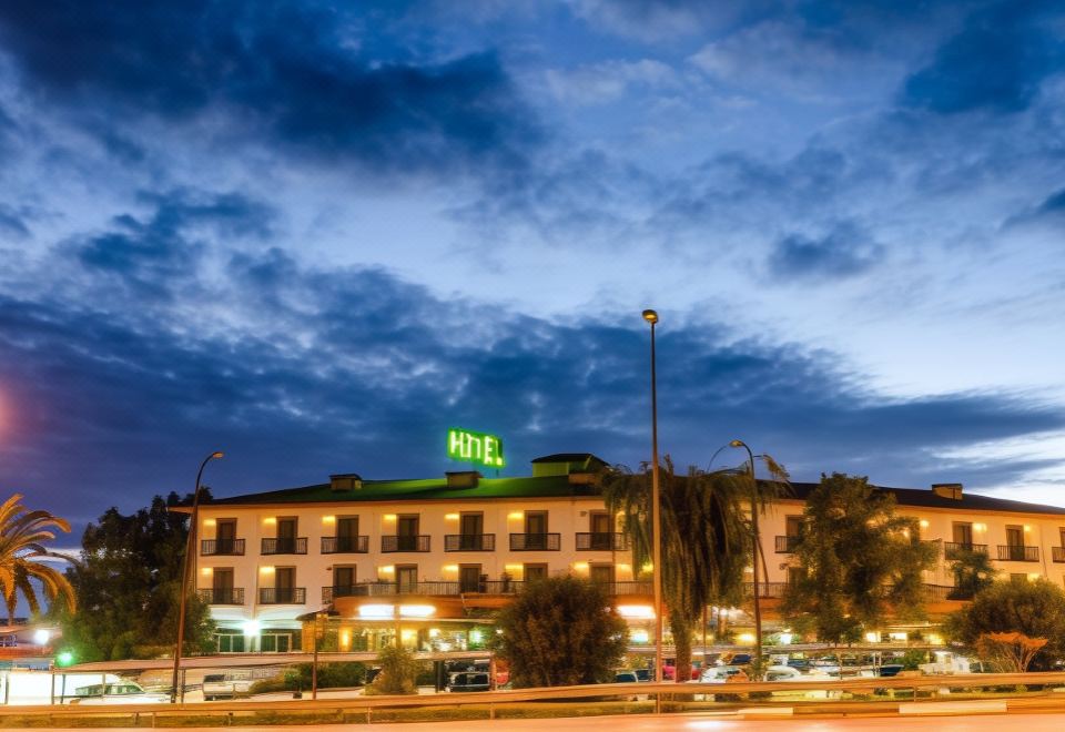 "a hotel building with the word "" hotel "" lit up at night , surrounded by other buildings and trees" at Hotel Zodiaco