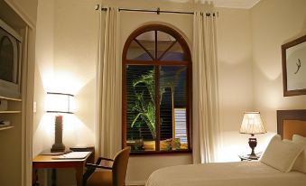 a bedroom with a large arched window , curtains , and a bed , providing a view of the outdoors at The Royal Hotel