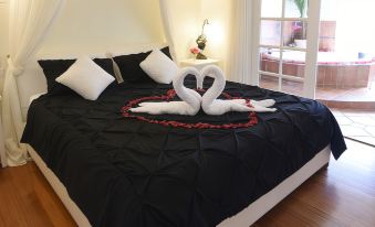 a bed with a black comforter and white pillows is adorned with two heart - shaped towels at Lakeside Cottage Luxury B&B
