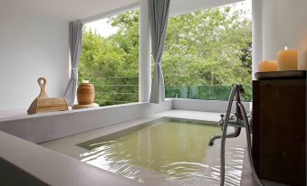 a large bathtub with a view of trees outside is situated in a room with white walls at Villa Moreeda