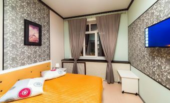 a bedroom with a bed , orange blanket , and curtains near a window that overlooks a building at Diana Hotel