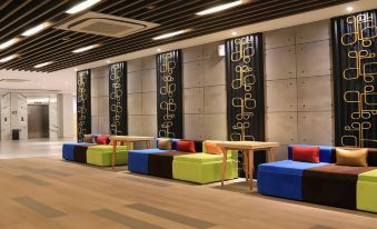 a modern lounge area with colorful couches and chairs , along with a long wooden table in the center at Ayaartta Hotel Malioboro