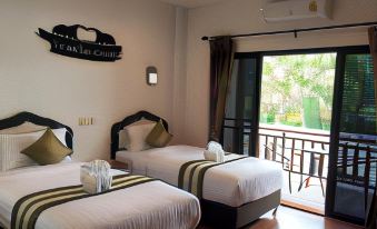 a hotel room with two beds , a window , and a balcony view , decorated with white bedding and black accents at Hugpua Hotel