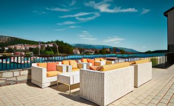 a terrace with comfortable seating and a view of the sea , under a clear blue sky at Hotel International