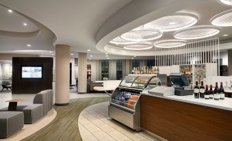 a modern cafe with a white ceiling , wooden reception desk , and various items on display at Courtyard Middletown Goshen