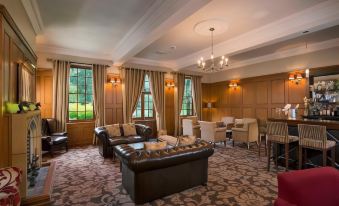 a spacious living room with a large couch , dining table , chairs , and windows , all decorated in neutral colors at Nunsmere Hall Hotel