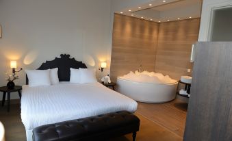 a modern bedroom with a large bed and a bathtub in the corner , creating a relaxing atmosphere at Fletcher Hotel - Restaurant Nautisch Kwartier