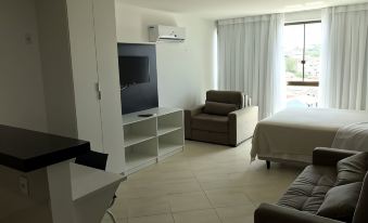 a modern living room with white walls , a flat - screen tv , a couch , and a dining table at Sophia II Residence Inn