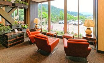 a room with orange leather chairs and tables , a lamp , and a view of the mountains outside the window at Mizno Hotel