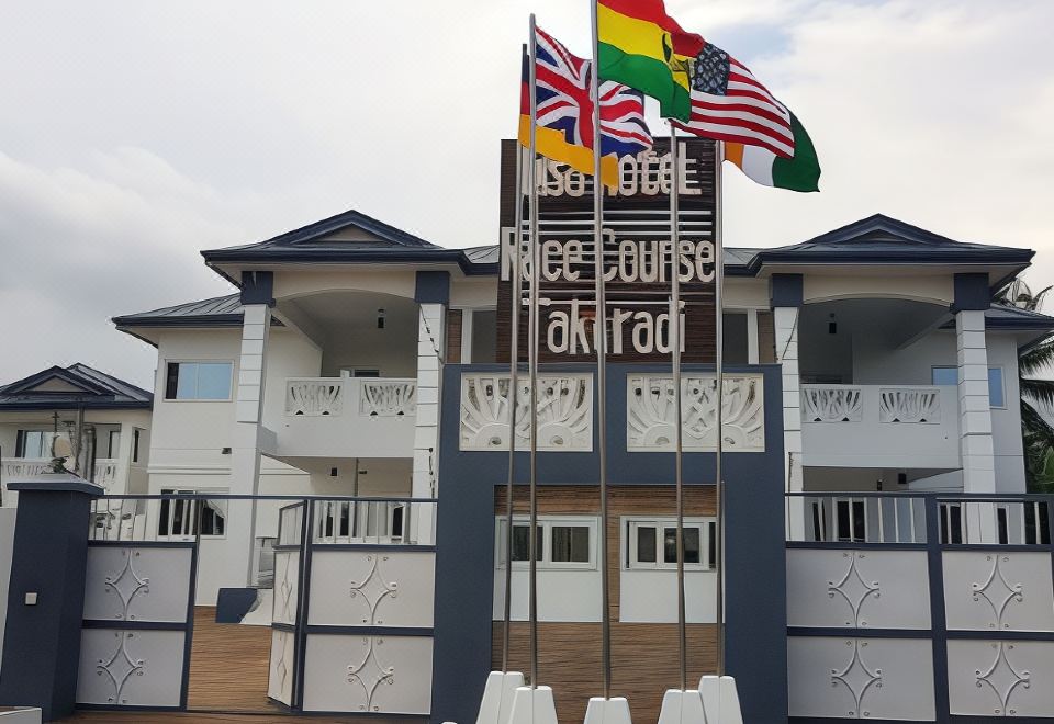 "a building with multiple flags and a sign that reads "" hotel "" prominently displayed on the front" at Ibisa Hotel