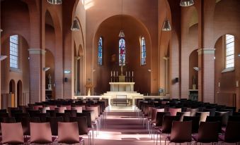 a large , empty church with rows of chairs and a cross in the center , under the church 's arched ceiling at Fletcher Kloosterhotel Willibrordhaeghe