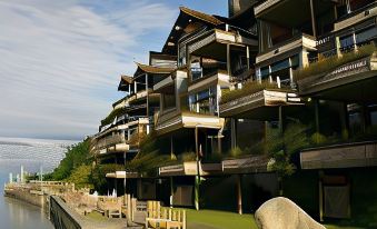 a large , modern apartment building situated near a body of water , with greenery surrounding it at The Inn at Langley