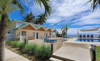 a row of small houses on the beach with a pool in front of them at Le Uaina Beach Resort