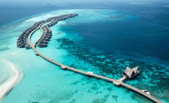 an aerial view of a long bridge spanning across the ocean , leading to a beach resort at Joali Maldives