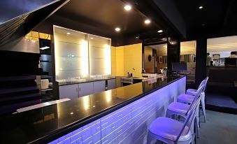 a modern bar with a white brick wall , black and yellow walls , and white stools around the counter at Hotel Woodland
