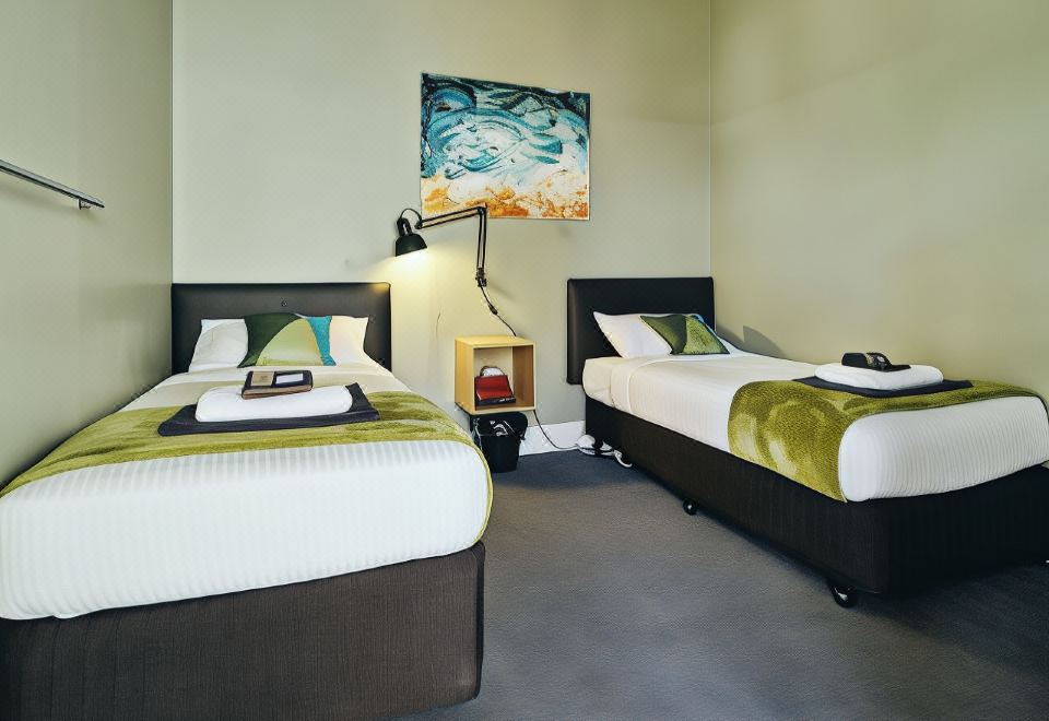 a hotel room with two beds , a nightstand between them and a painting on the wall at Black Diamond Lodge