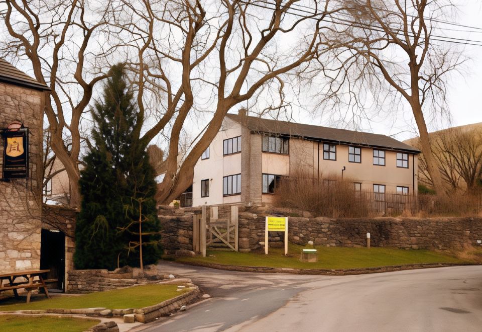 a building with a tree in front of it , and a sign on the left side of the building at YHA Malham