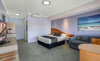 a modern bedroom with a large bed , a couch , and a tv . the room is well - organized and appears to be clean and at Shellharbour Village Motel