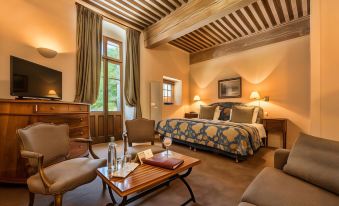 a hotel room with a large bed , a couch , and a tv . the room is well - appointed and spacious at Abbaye de Talloires