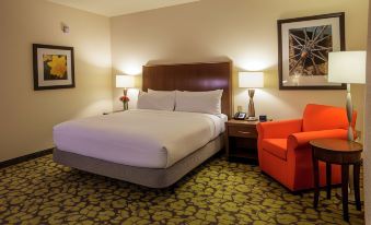 a hotel room with a king - sized bed , a chair , and two lamps on either side of the bed at Hilton Garden Inn Uniontown