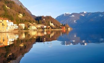 a serene landscape of a mountainous area with snow - capped peaks , reflecting in a calm lake at Hotel Stella d'Italia