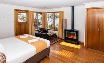 a spacious bedroom with hardwood floors , a large bed , and a fireplace , providing a cozy atmosphere at Lake St Clair Lodge