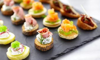 a platter filled with a variety of appetizers , including meat , fish , and bread , on a dining table at Delamore Lodge