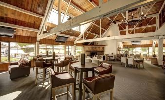 a large , open room with wooden beams and a high ceiling has several chairs and tables at Edgewater Hotel