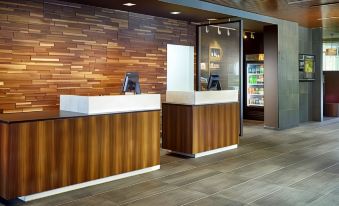 a modern hotel lobby with wooden walls , a wooden reception desk , and an interactive kiosk at Courtyard LaGrange
