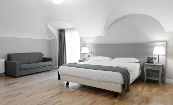 a modern bedroom with white walls , wooden floors , and a large bed , accompanied by a couch and a window at Hotel de Ville