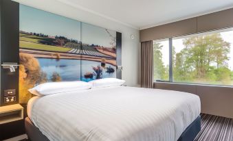 a large bed with white linens is situated in a room with a large mural on the wall at Hotel Launceston