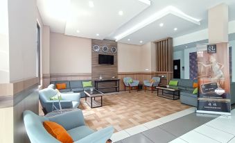 a modern , well - lit living room with multiple chairs and couches arranged in an open space at El Hotel Malang