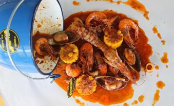 a large plate filled with a variety of seafood , including shrimp , mussels , and scallops , served on a white plate at Lam-Tong Resort