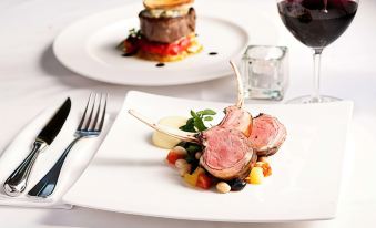 a dining table with two plates of food , one containing meat and the other vegetables at Farmhouse Inn