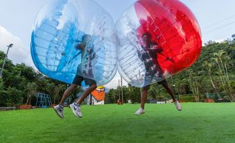 two young men wearing inflatable balls , one on each side of the grass field at Hotel Cham Cham Tainan