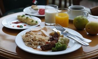 a dining table with a variety of food items , including meat , rice , and vegetables , accompanied by cups of coffee and juice at Resor Tuban Tropis