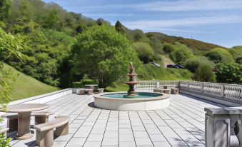 a white tiled patio with a fountain in the center , surrounded by benches and chairs at Abbeyglen Castle Hotel