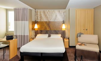 a hotel room with a double bed , two lamps , and a couch , all decorated in neutral colors at Ibis Longwy Mexy