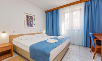 a hotel room with a double bed and a single bed , as well as a tv and a window at Maistra Select Riva Apartments