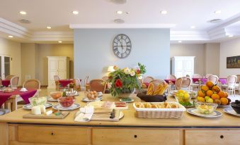 a dining table is set with a variety of food items and utensils , including bowls , forks , knives , and spoons at Hotel Punta Nord Est