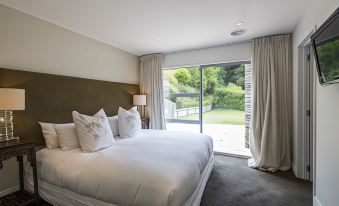 a large bed with white linens is situated in a room with a sliding glass door leading to an outdoor patio at Riverview Retreat Holiday Home by MajorDomo