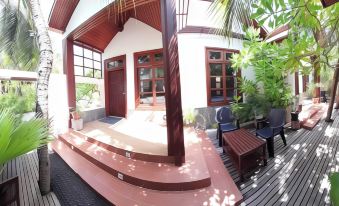 a panoramic view of a house with a wooden exterior and red roof , featuring a wooden deck and lush greenery surrounding the house at Beach Cottage