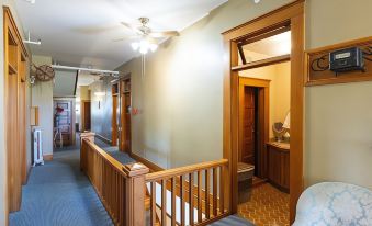 a hallway with a wooden staircase leading to the second floor , featuring a fan and a bench at Balch Hotel