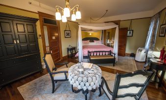 a bedroom with a bed , table , and chairs is shown with a chandelier hanging above at Balch Hotel