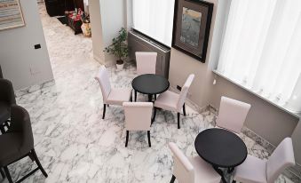 a modern living room with black and white marble flooring , white walls , and pink chairs around black tables at Hotel de Ville